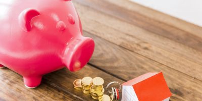 piggybank-stacked-coins-house-key-wooden-desk